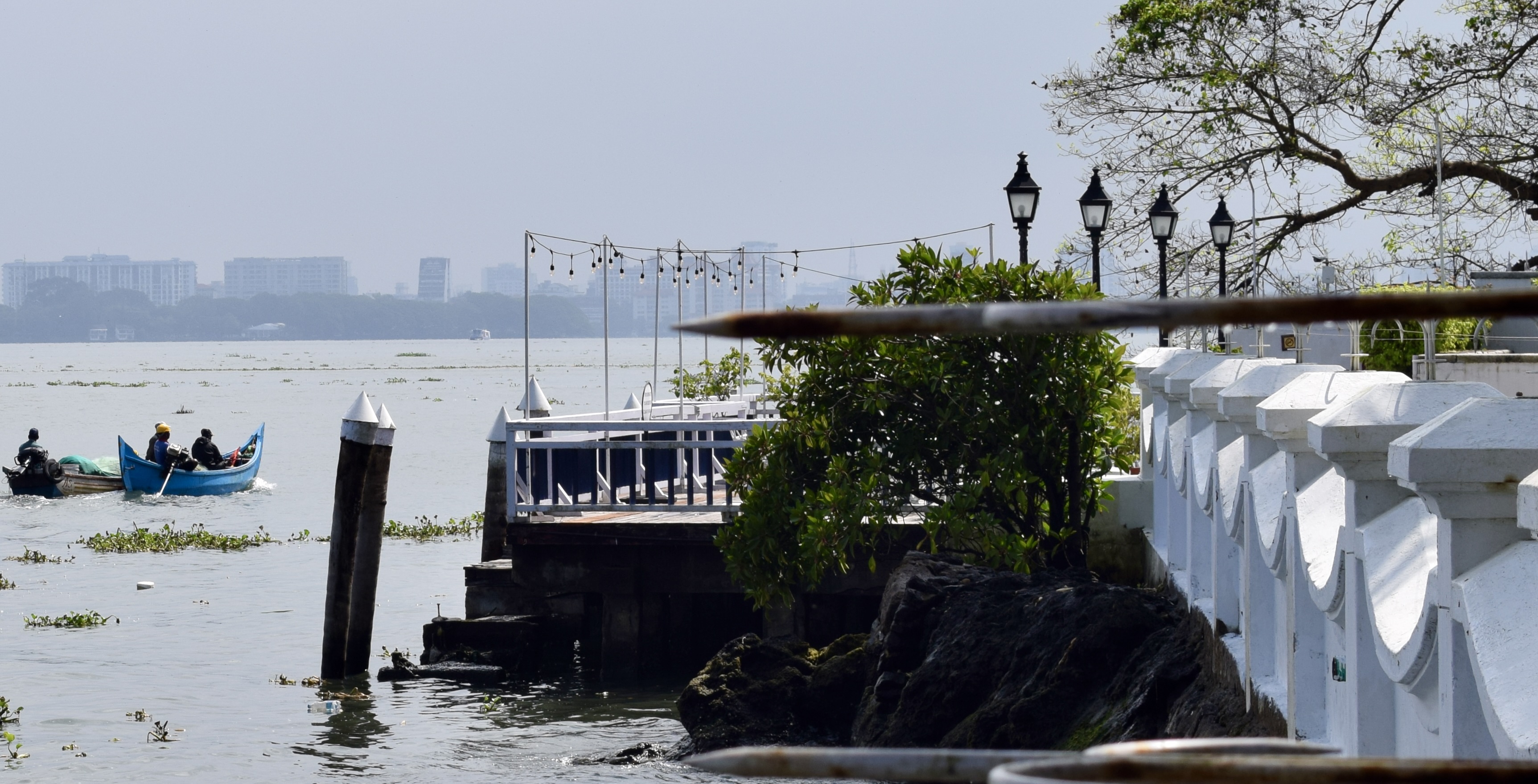 A blue fishing boat passing the waterfront promenade in Kochi
